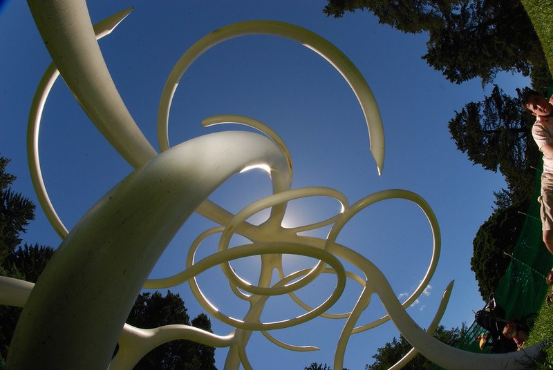 Curving white public sculpture photographed against a blue sky.