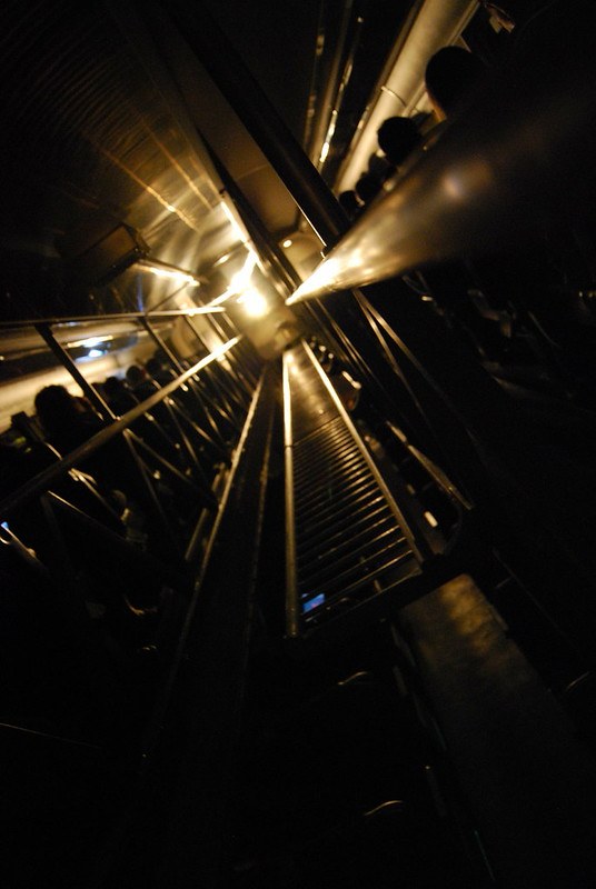 Warm light and metal lines inside a transit or escalator space.
